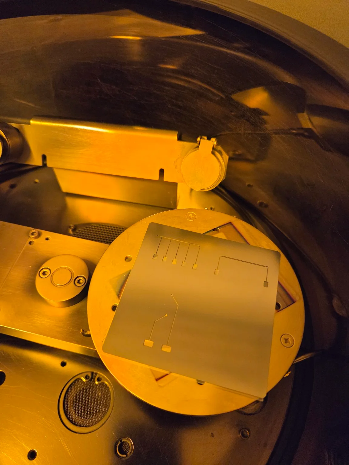 Electrode-patterned substrate inside deposition equipment under amber laboratory lighting